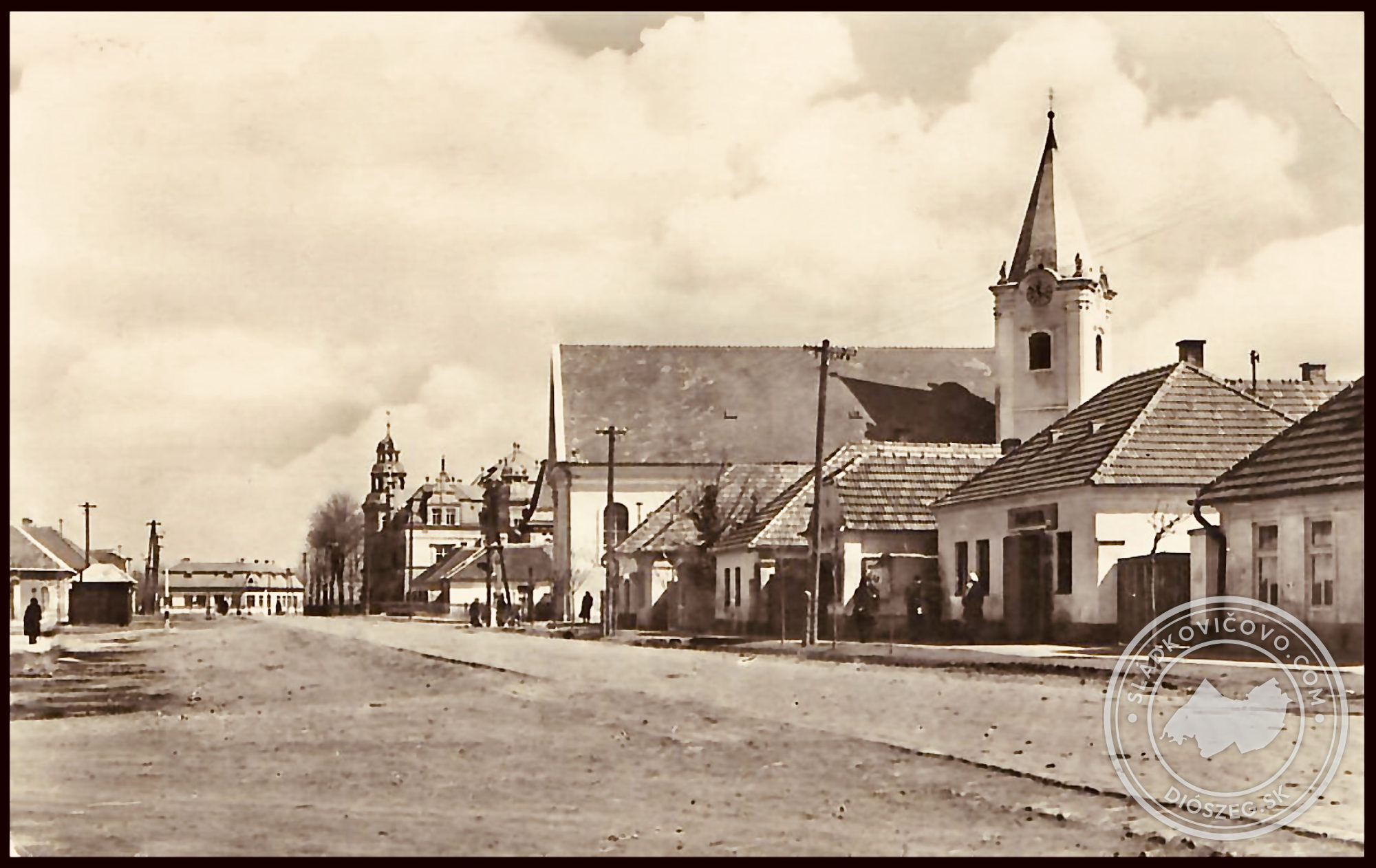 Na fotografii z päťdesiatych rokov 20. storočia je námestie ešte s nespevneným povrchom, r.k. kostolom, na pozadí s kaštieľom a budovou Mestského úradu (vtedy MNV) a vľavo je bývalá trafika.